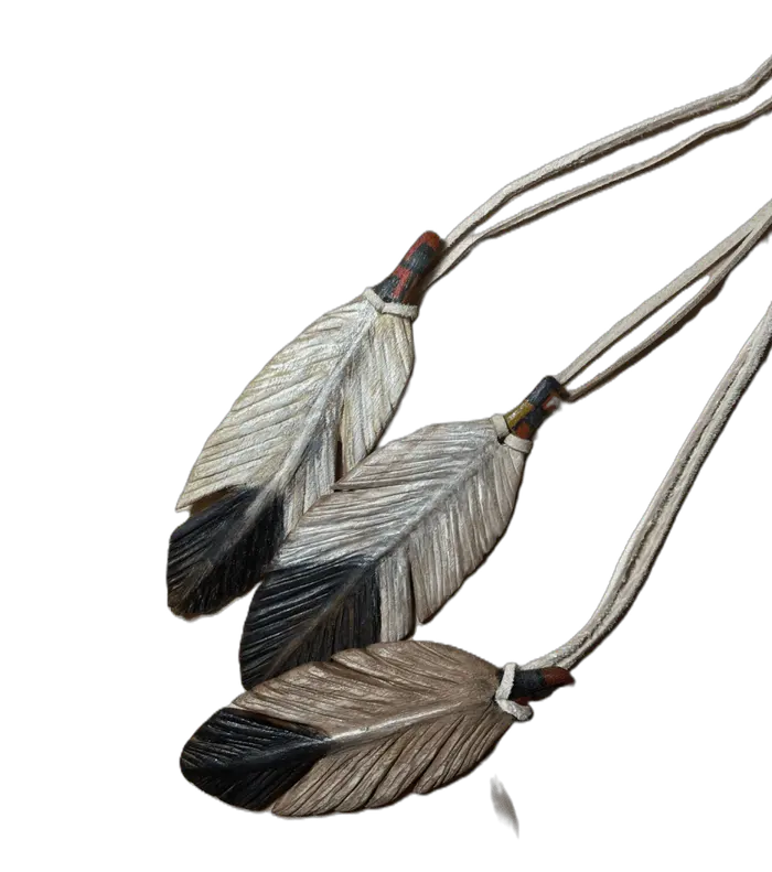 Three hand-carved prayer feathers in black, white and natural wood, suspended from cords